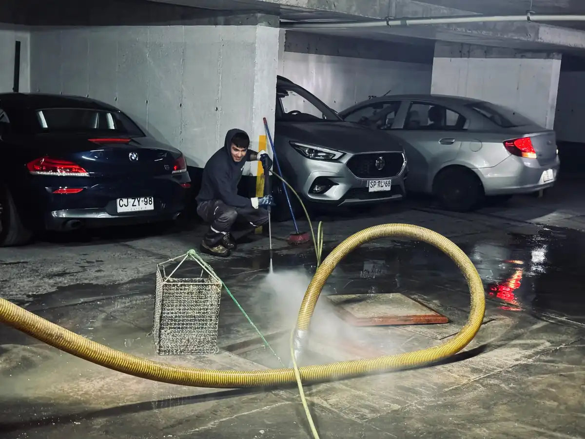 Técnico trabajando en una cámara de alcantarillado dentro de un estacionamiento