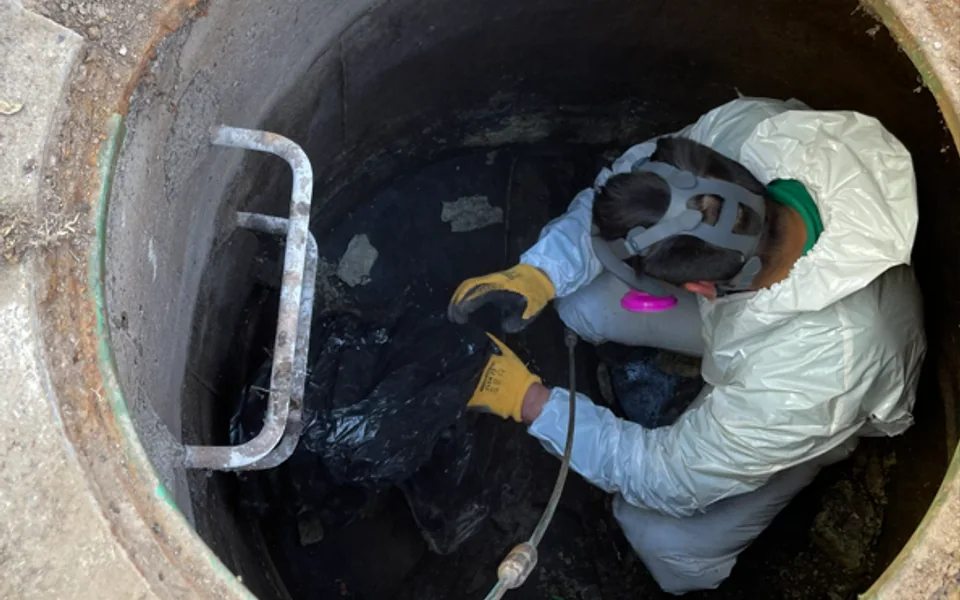 Trabajador con equipo de protección operando varillas dentro de una cámara